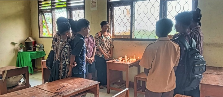 Wali Kelas dan teman-teman almarhum S. T. N (Noni) tengah menyalakan lilin dan berdoa mengenang almarhum Noni. 