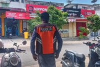 Juru Parkir Dishub Sikka saat mengatur parkir di salah satu jalan di Kota Maumere.