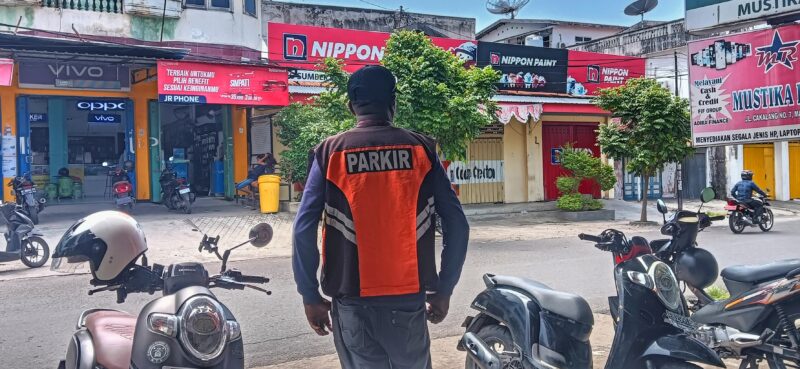 Juru Parkir Dishub Sikka saat mengatur parkir di salah satu jalan di Kota Maumere.